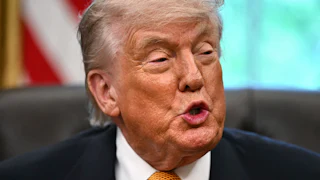 Donald Trump speaks while sitting at his desk in the Oval Office