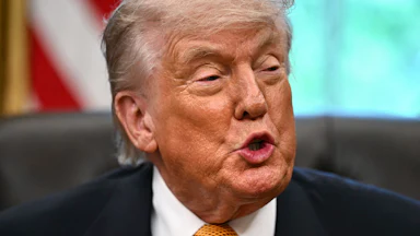 Donald Trump speaks while sitting at his desk in the Oval Office
