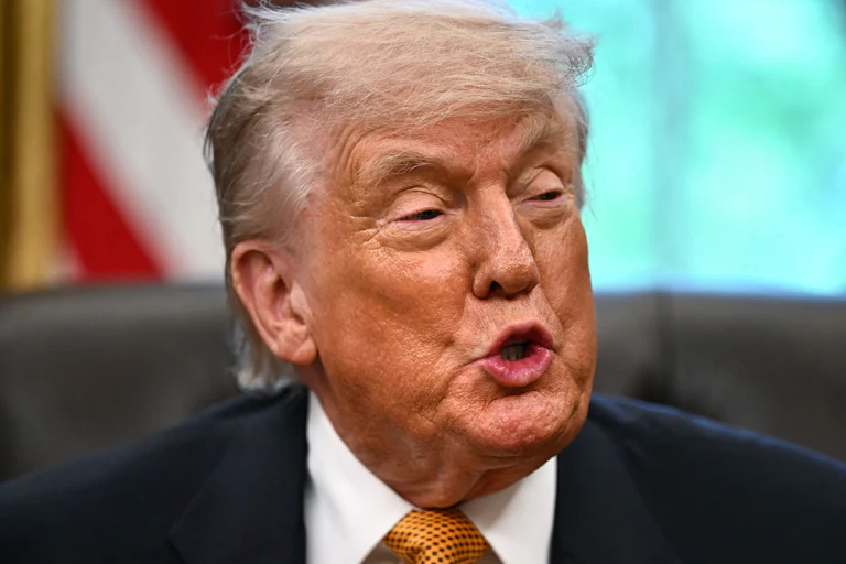 Donald Trump speaks while sitting at his desk in the Oval Office