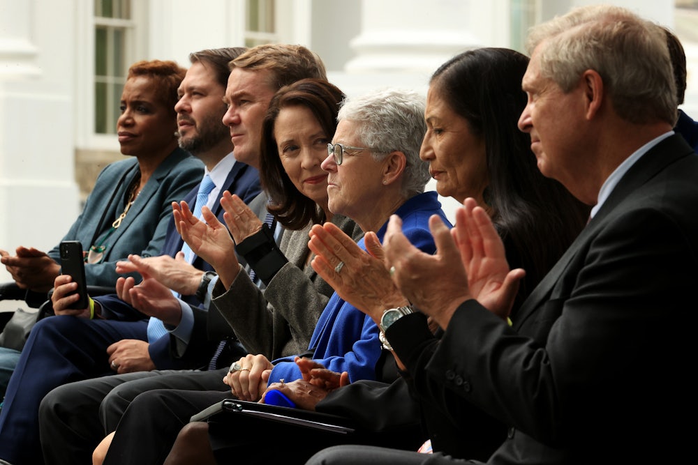 Gina McCarthy sits surrounding by people clapping. She clasps her hands.
