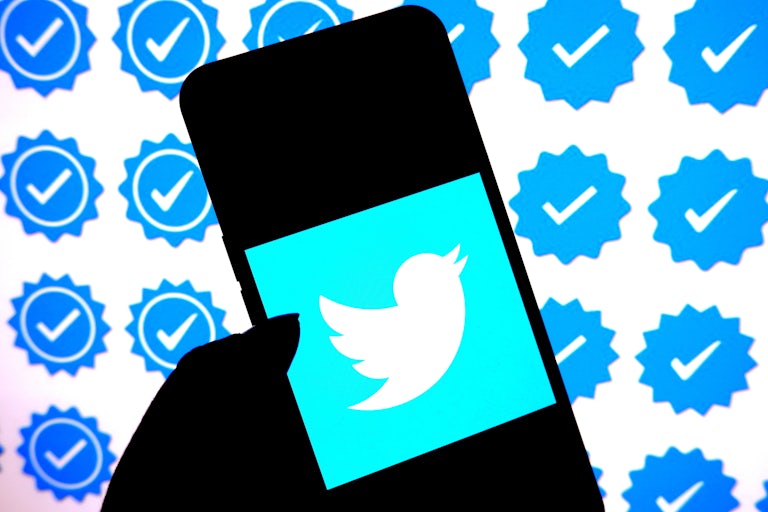  In this photo illustration, a Twitter logo is displayed on a smartphone with Blue Tick logo in the background.