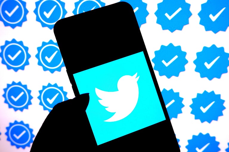 In this photo illustration, a Twitter logo is displayed on a smartphone with Blue Tick logo in the background.
