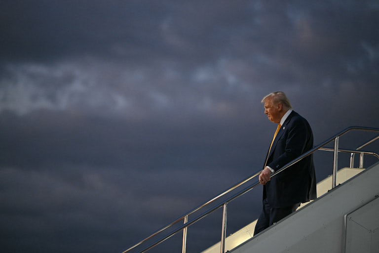 Donald Trump holds the stairs handrail while disembarking from Air Force One
