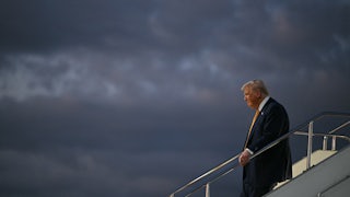 Donald Trump holds the stairs handrail while disembarking from Air Force One