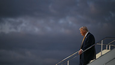 Donald Trump holds the stairs handrail while disembarking from Air Force One