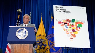 RFK Jr. stands at a podium next to a poster of the new, inverted food pyramid.