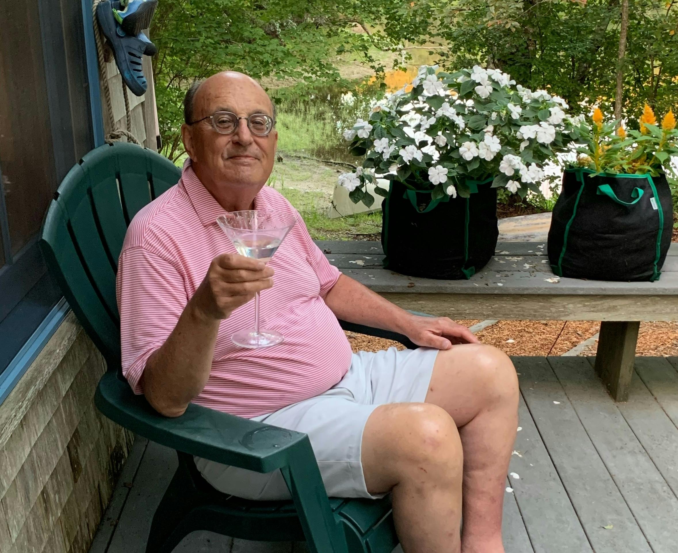 Longtime New Republic staff writer Walter Shapiro holds a martini while sitting in a deck chair.