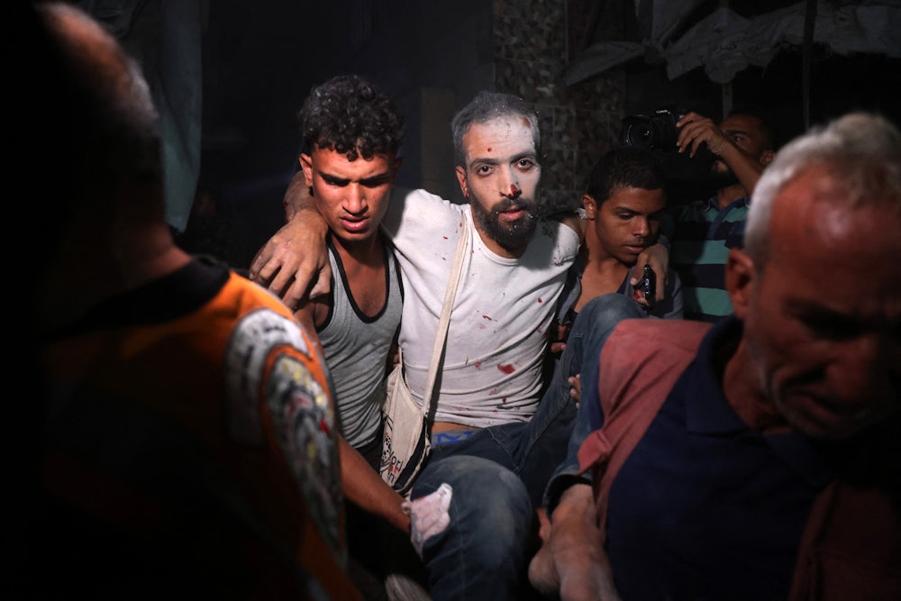 Palestinians help a man injured in an Israeli strike