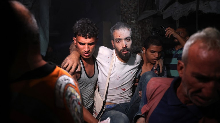 Palestinians help a man injured in an Israeli strike