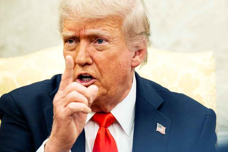 Donald Trump raises his finger and speaks while sitting in the Oval Office