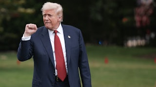 Donald Trump raises his fist while walking across the White House lawn