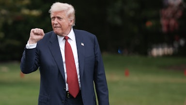 Donald Trump raises his fist while walking across the White House lawn