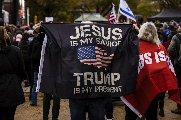 A person holds a banner reading "Jesus is my savior. Trump is my president."