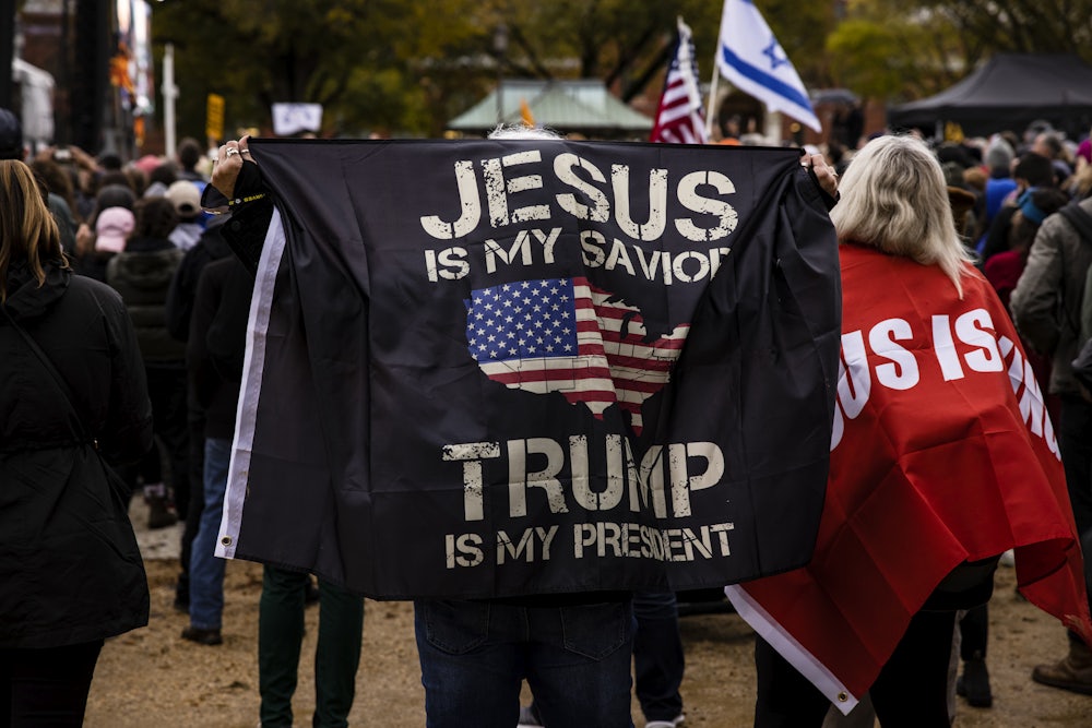 A person holds a banner reading "Jesus is my savior. Trump is my president."