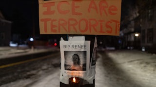 A sign that says "ICE are terrorist" hangs above a photo of Renee Good, who was shot dead by ICE in Minneapolis, Minnesota. The photo says, "RIP Renee. Murdered by ICE"