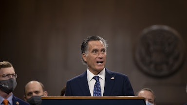 Senator Mitt Romney speaks to a group of masked members of Congress at the Capitol