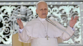 Pope Leo gestures while speaking into a microphone