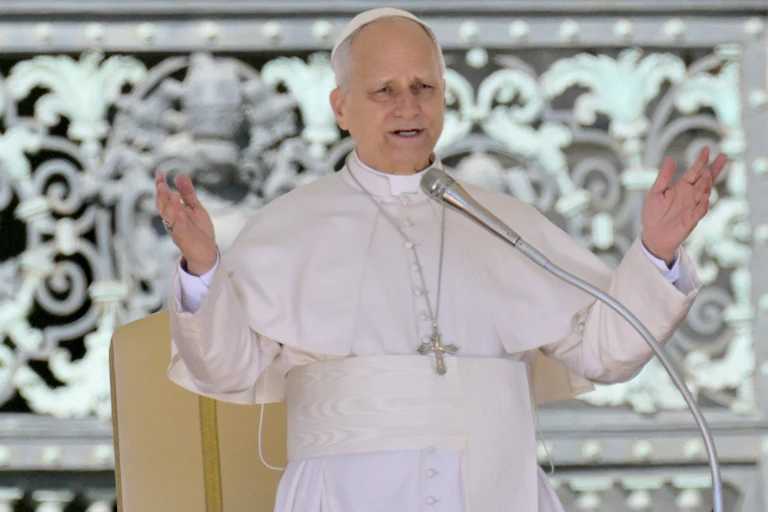 Pope Leo gestures while speaking into a microphone