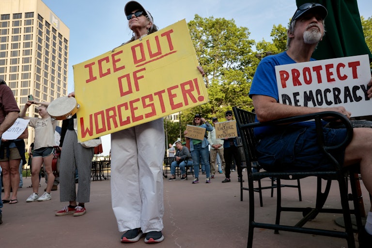 People hold up signs at a protest against ICE in Worcester, Massachusetts