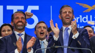 Eric Trump and Donald Trump Jr. clap at NASDAQ while standing in front of Zach Witkoff and a group of other men.