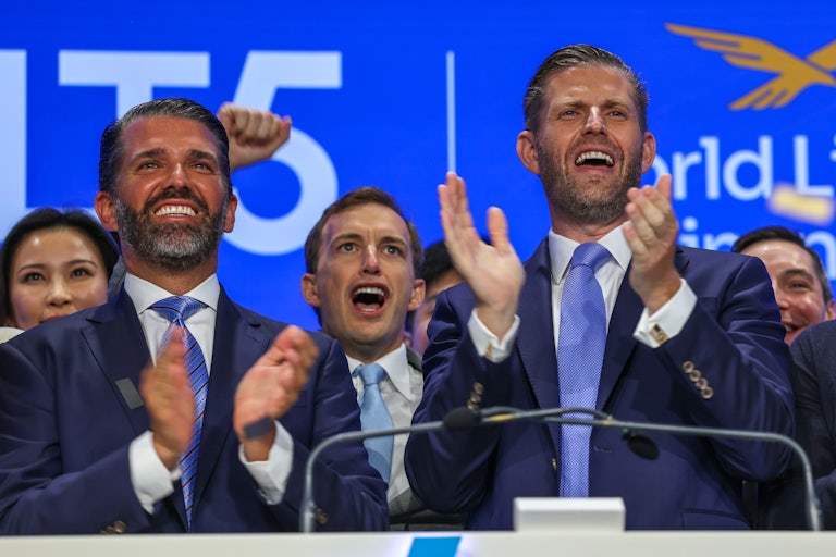 Eric Trump and Donald Trump Jr. clap at NASDAQ while standing in front of Zach Witkoff and a group of other men.