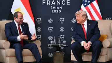 Egypt’s President Abdel Fattah El-Sisi and U.S. President Donald Trump sit on two armchairs as they smile at each other.