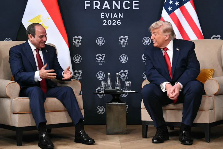 Egypt’s President Abdel Fattah El-Sisi and U.S. President Donald Trump sit on two armchairs as they smile at each other.