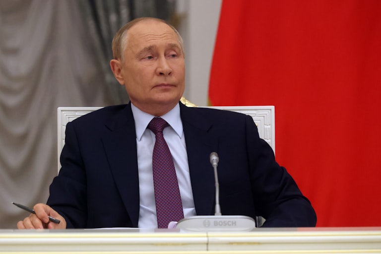 Russian President Vladimir Putin sits at a table