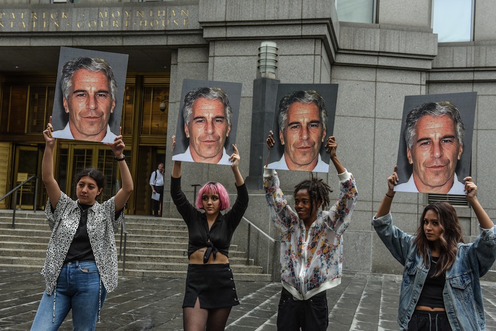 A protest group called “Hot Mess” hold up signs of Jeffrey Epstein