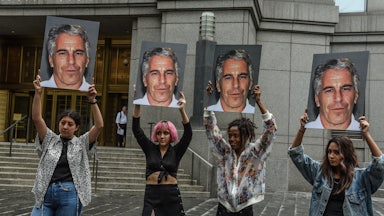 A protest group called “Hot Mess” hold up signs of Jeffrey Epstein