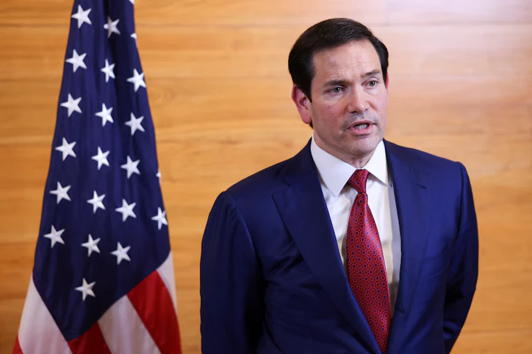 Secretary of State Marco Rubio speaks while standing in an airport departure lounge