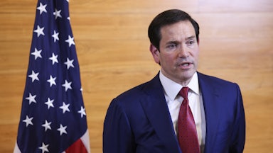 Secretary of State Marco Rubio speaks while standing in an airport departure lounge