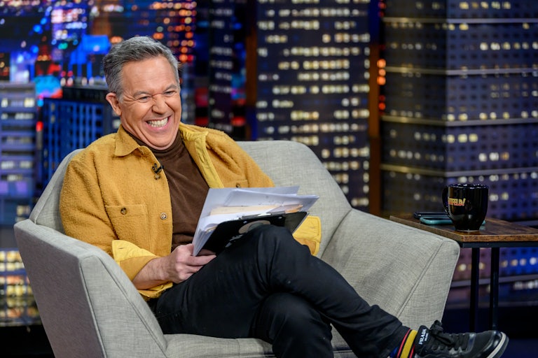 Greg Gutfeld leans back in a chair and laughs hysterically to something that is probably not funny