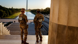 Two members of the National Guard stand in the Lincoln Memorial and face the Washington Monument