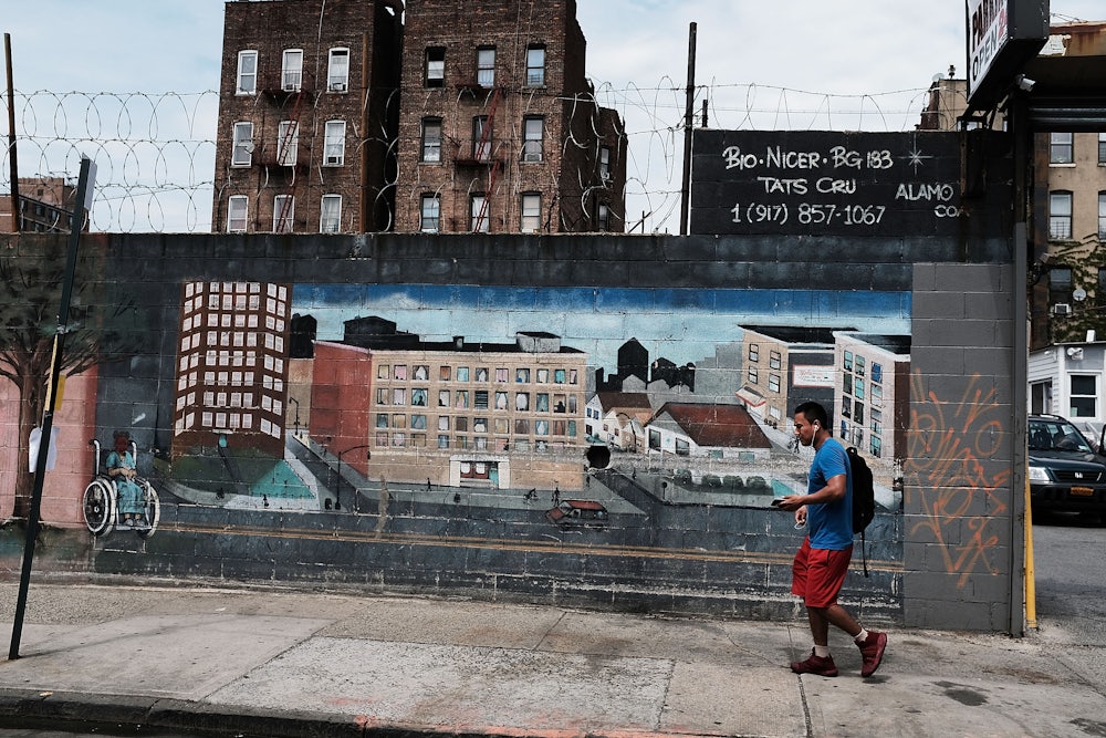 a man walks by a mural in the south bronx showing different types of housing