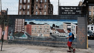 a man walks by a mural in the south bronx showing different types of housing