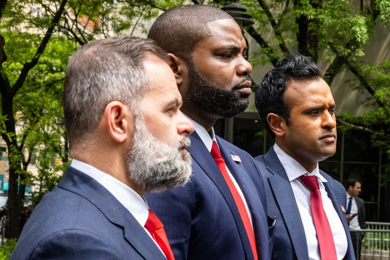 Three men—two Republican representatives and Vivek Ramaswamy—wearing blue suits and red ties stand in a line outside a Manhattan courthouse.