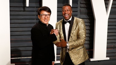 Jackie Chan and Chris Tucker grasp each other's hands as they smile for the cameras.