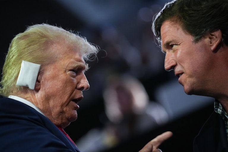 Donald Trump, wearing a bandage on his ear following the attempt on his life at Butler, PA last summer, talks to Tucker Carlson
