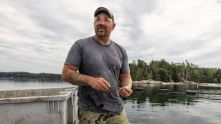 Graham Platner shucks oysters at the farm he co-runs in the Frenchman Bay in Maine, June 25, 2025.