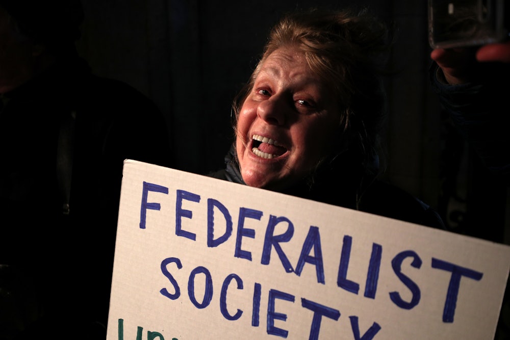 A protester holds a sign criticizing the Federalist Society at a 2020 event.