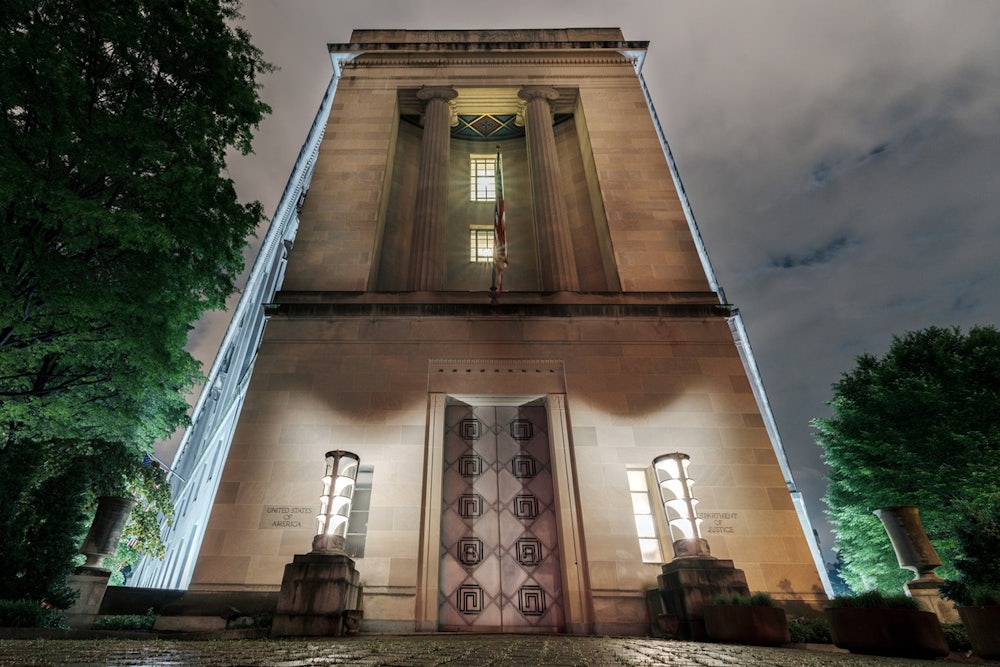 The corner of the Department of Justice building is illuminated at night.