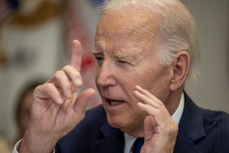 Joe Biden speaking and making hand gestures near his head.