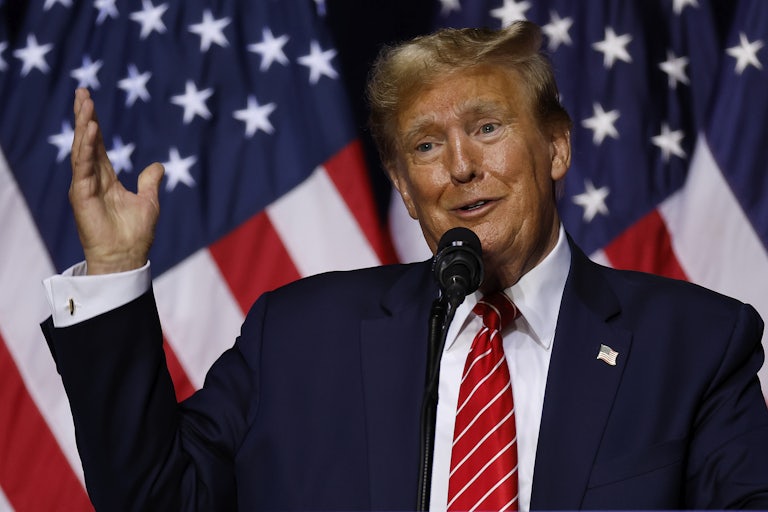 Donald Trump speaks at a mic and makes a very weird face. A U.S. flag is behind him.