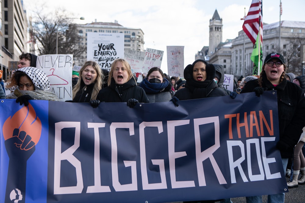 Demonstrators carry a banner reading "Bigger Than Roe."