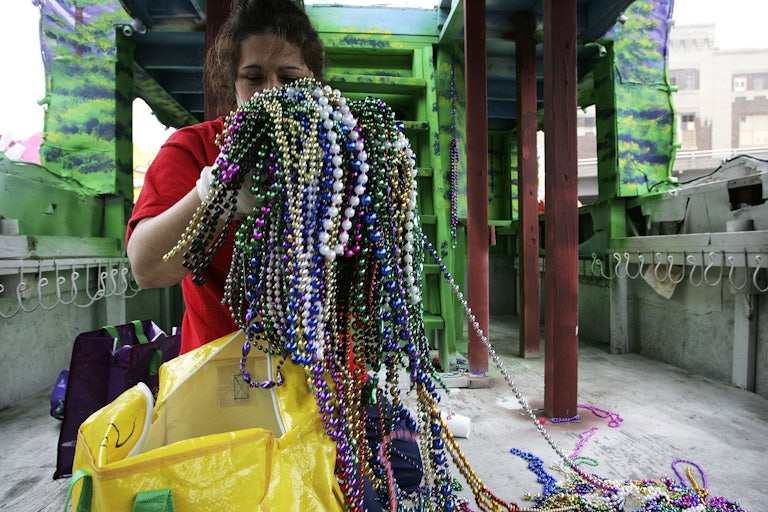 A worker holds a huge mass of Mardi Gras beads.