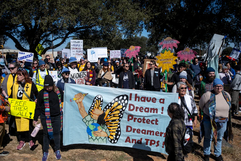 A group of protesters hold up banners against the Trump administration's immigration policies, with one banner reading "I have a dream! Protect Dreamers and TPS!"