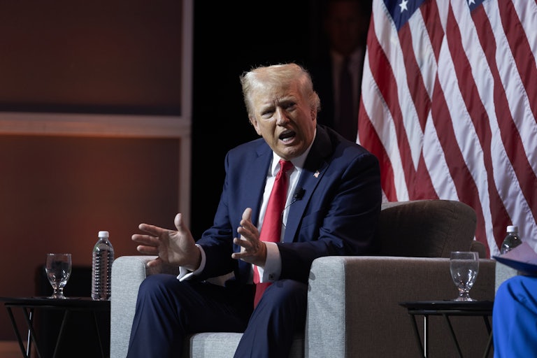 Donald Trump, seated, yells and splays his hands out