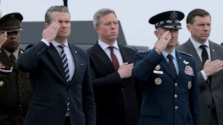Defense Secretary Pete Hegseth and Army Secretary Daniel Driscoll stand at attention alongside three other men.