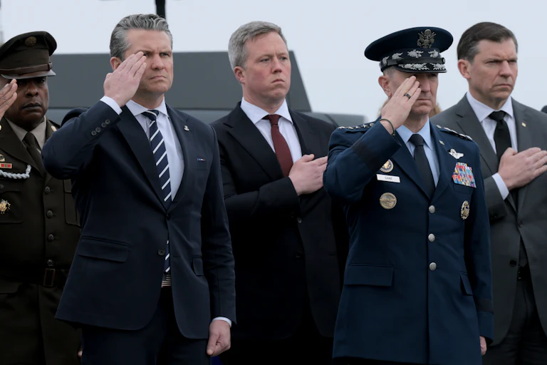 Defense Secretary Pete Hegseth and Army Secretary Daniel Driscoll stand at attention alongside three other men.